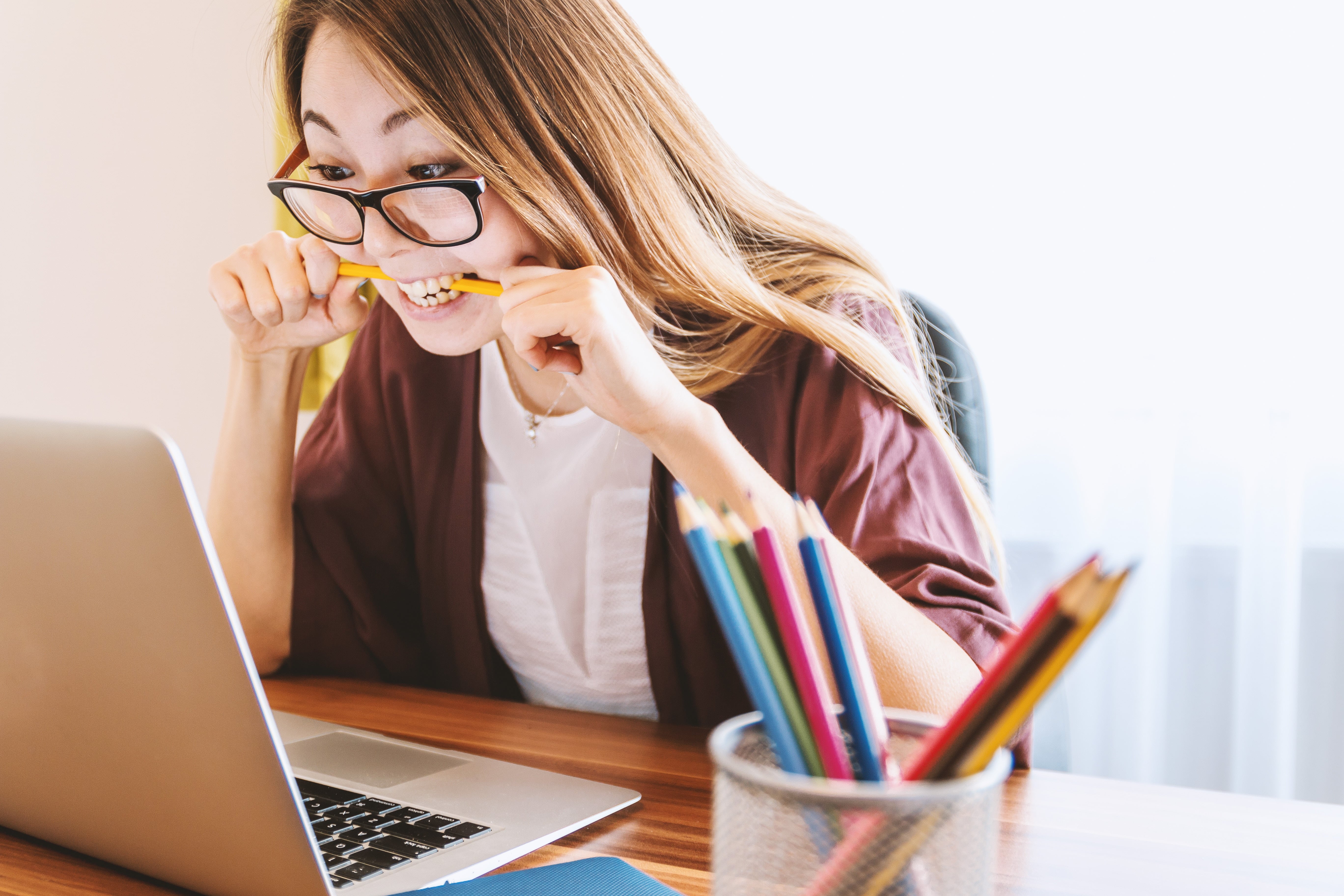 A stressed woman bites on a pencil at her work desk, which isn’t a situation of acute, but chronic stress