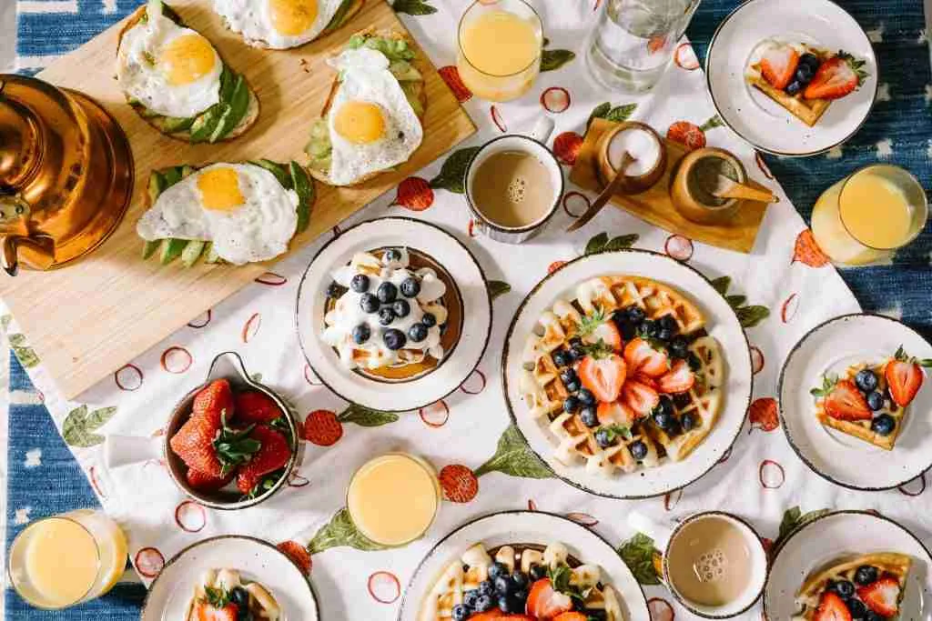 Bunter Frühstückstisch mit Eiern, Waffeln, Erdbeeren und Orangensaft