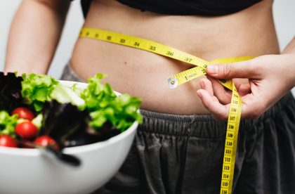 A woman taking a waist measurement to assess if stress can cause belly fat