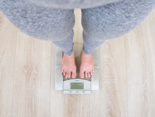 A woman on scale asking herself, if chronic stress can cause rapid weight gain without overeating